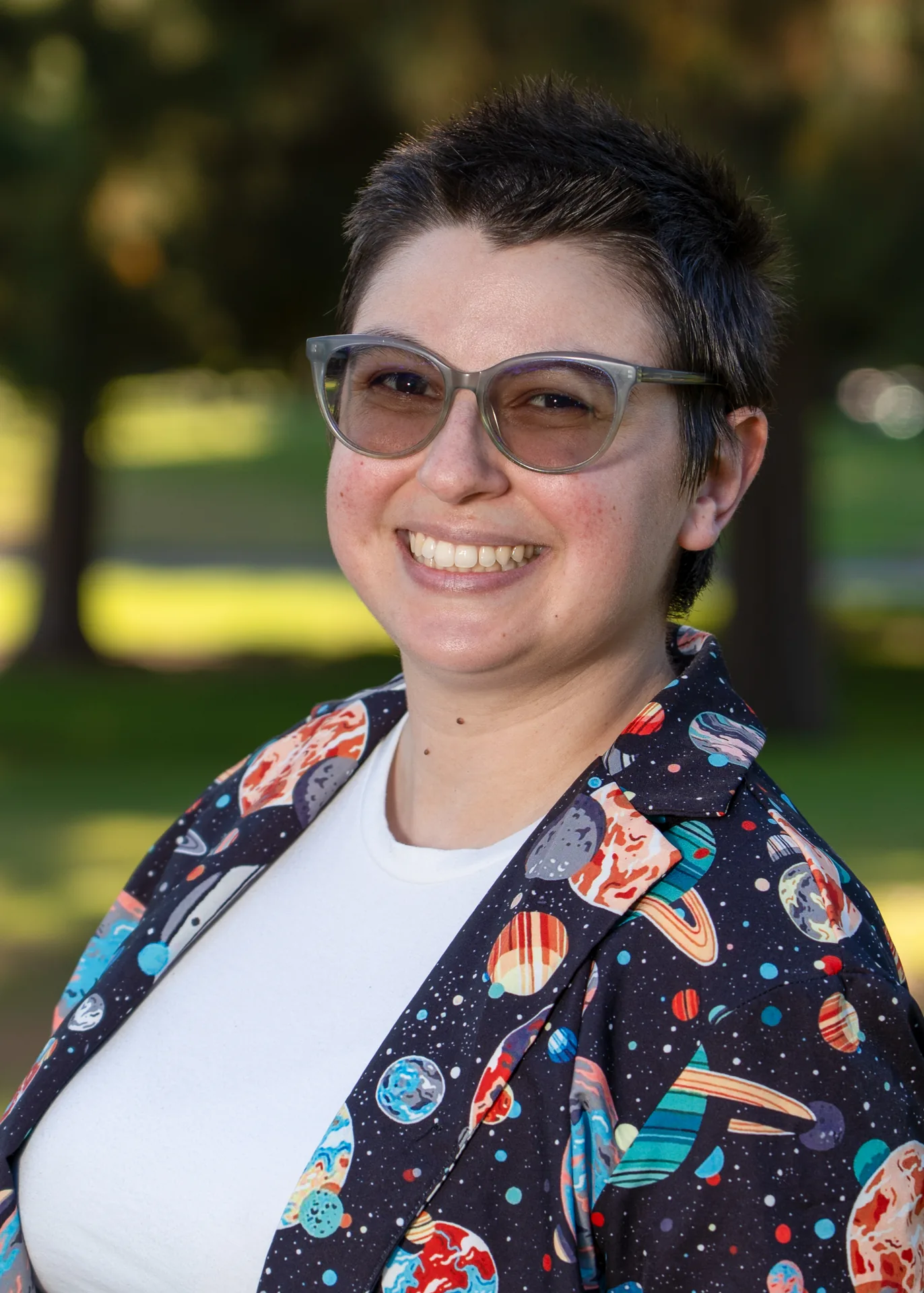 Natural light headshot of a smiling woman wearing glasses, photographed outdoors