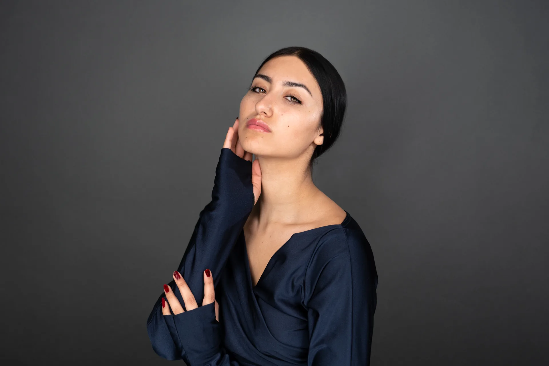 Lifestyle portrait of a woman photographed against a grey backdrop